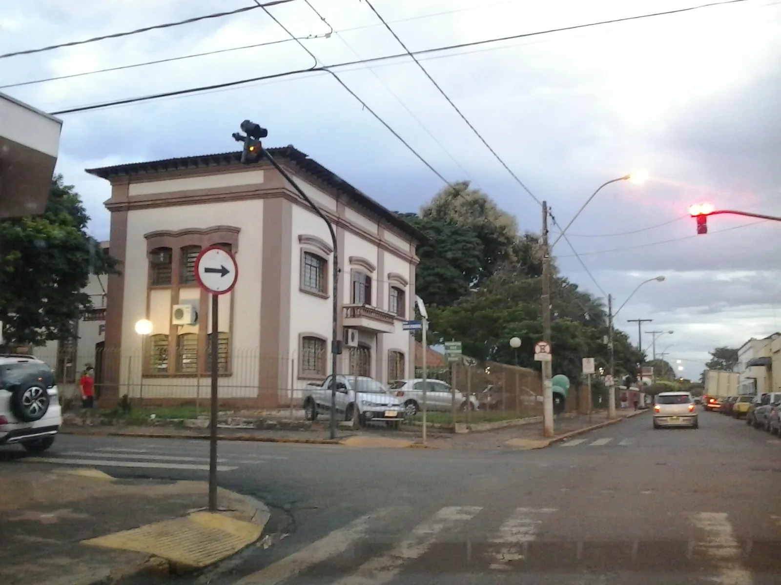 Esquina de São Joaquim da Barra com um sobrado antigo, semáforo e carros, num fim de tarde nublado