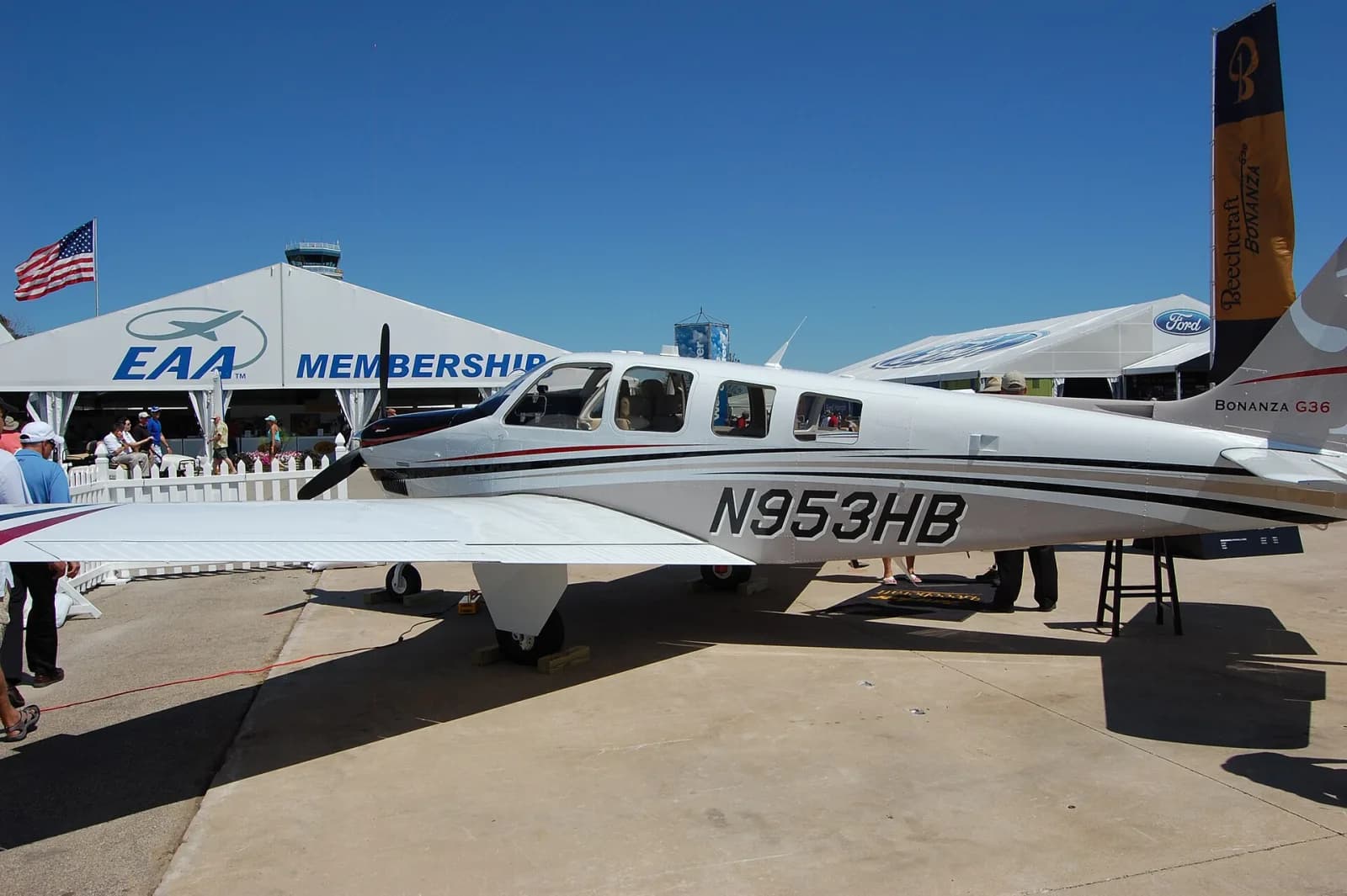 Beechcraft Bonanza G36 branco exposto num pátio de feira, diante de uma tenda da EAA