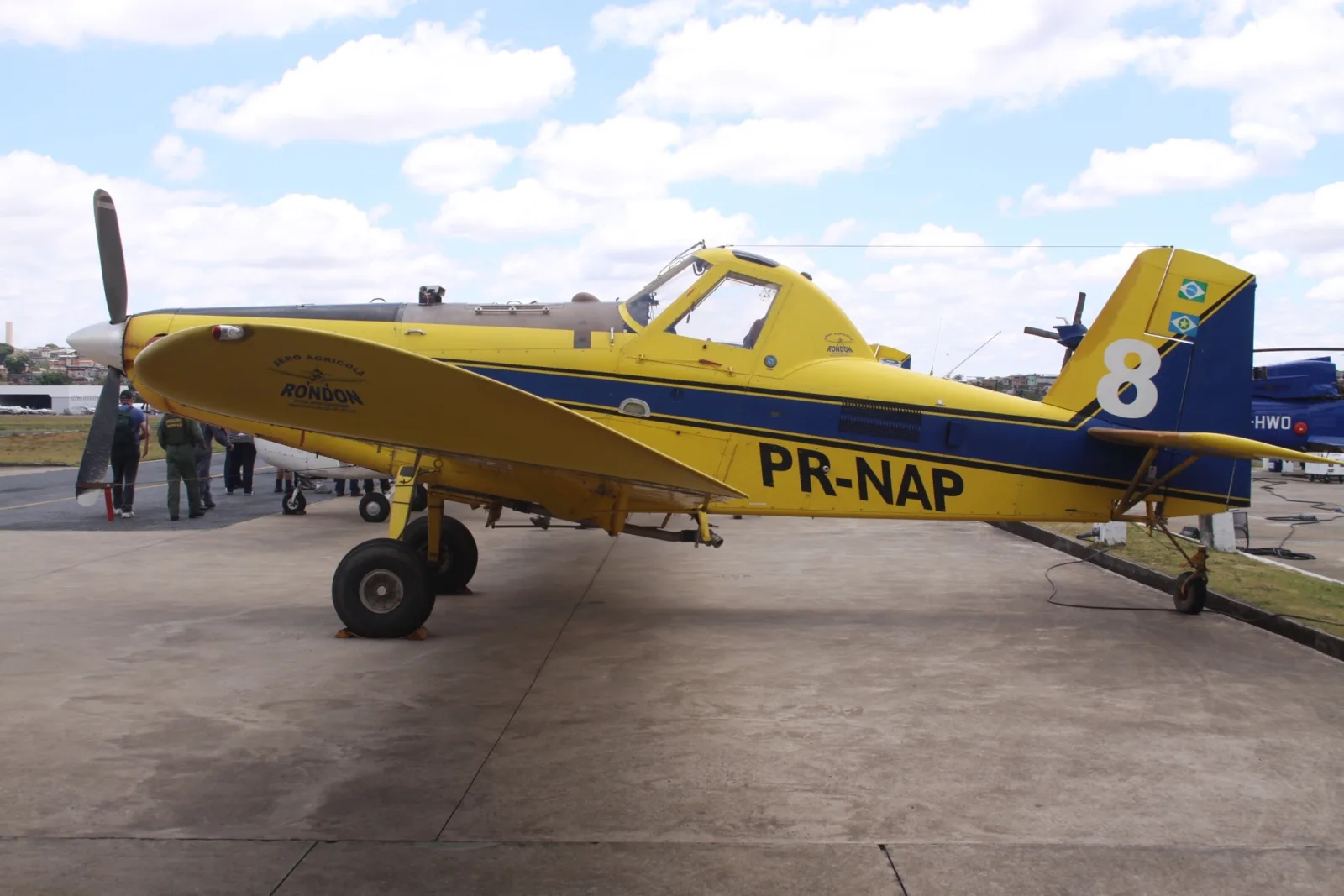Avião agrícola Air Tractor amarelo e azul, matrícula PR-NAP, estacionado no pátio de um aeroporto
