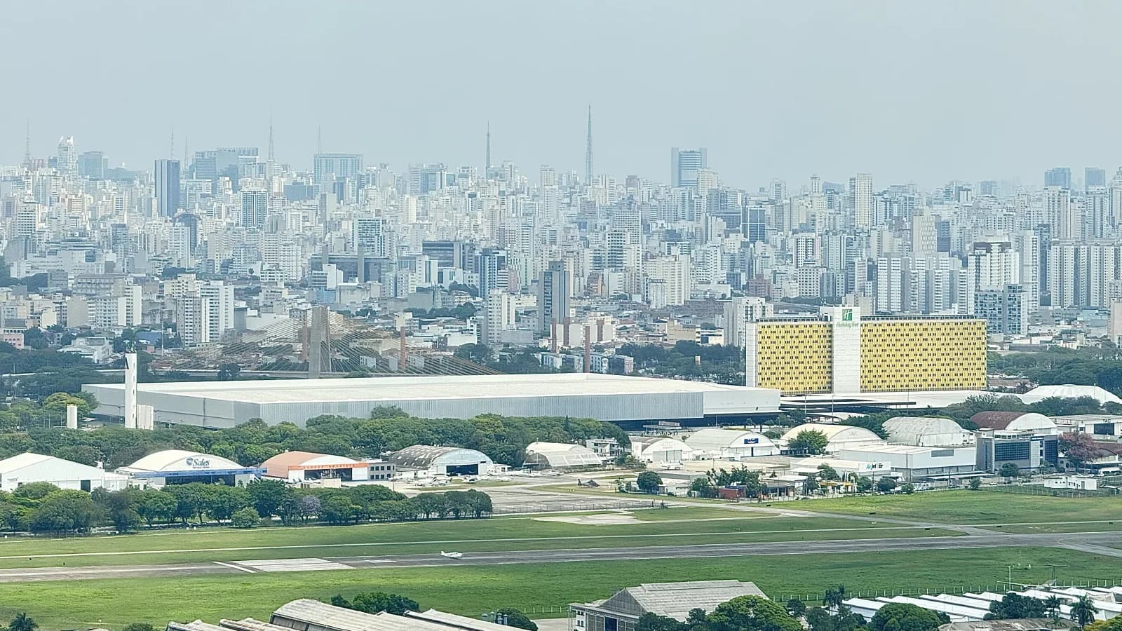 Vista aérea da pista do Campo de Marte com o pavilhão do Anhembi e a zona norte de São Paulo ao fundo