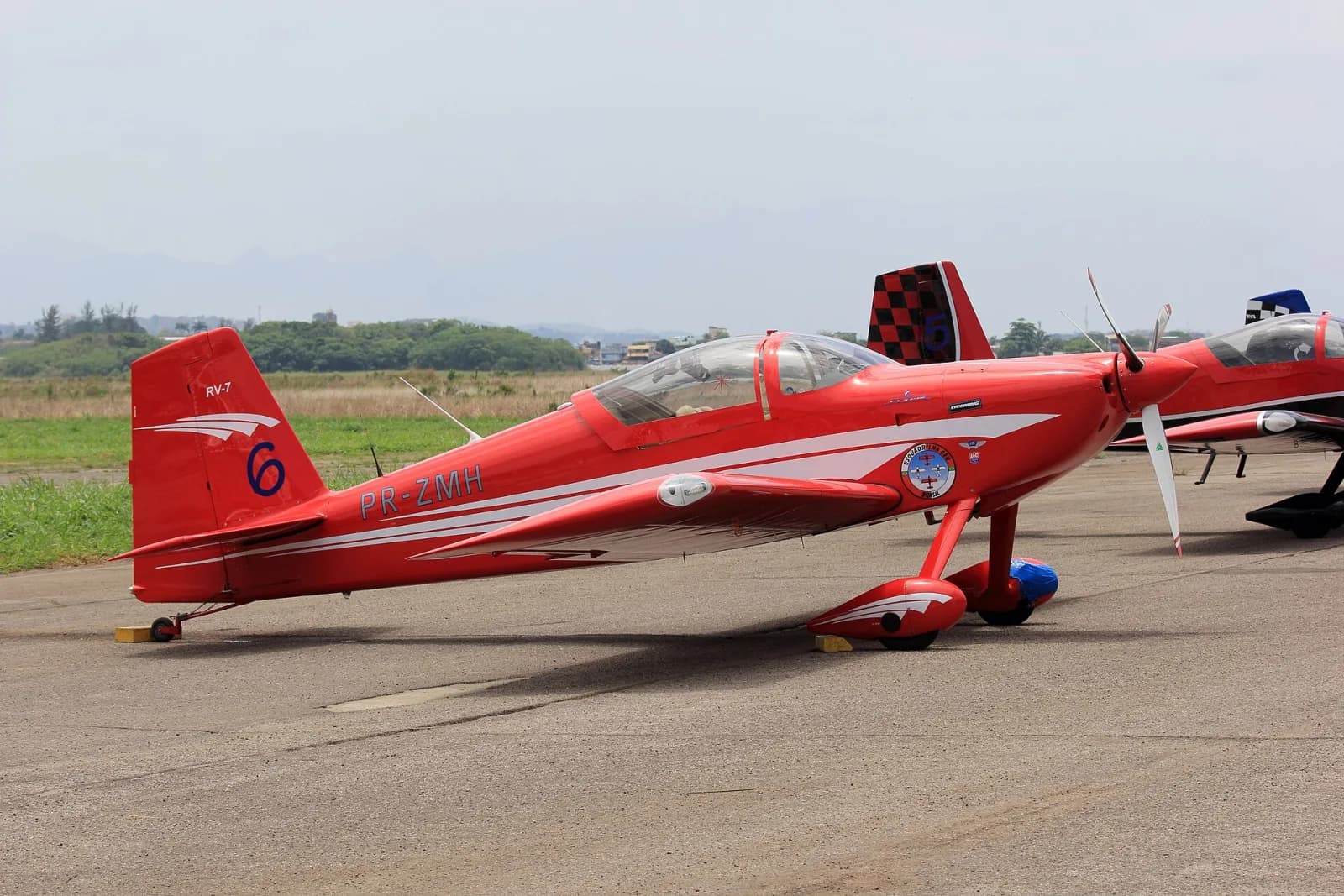 Avião experimental RV-7 vermelho, matrícula PR-ZMH, com o emblema da Esquadrilha CEU, estacionado no pátio