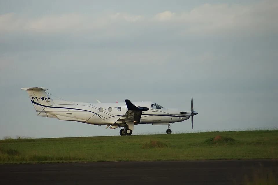 Turboélice Pilatus PC-12 branco com faixas azuis, prefixo PT-WKF, rodando na pista sob céu nublado