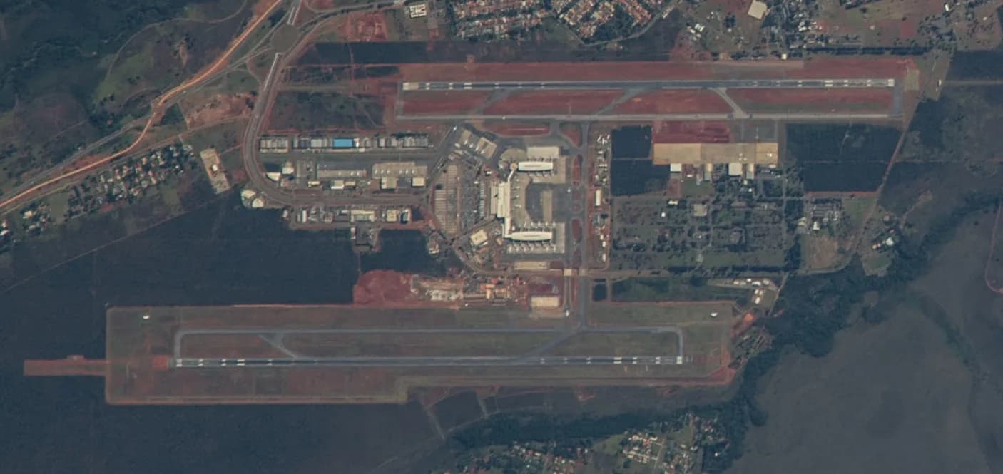 Vista de cima do Aeroporto Internacional de Brasília, com as duas pistas paralelas, os pátios e os terminais cercados de cerrado